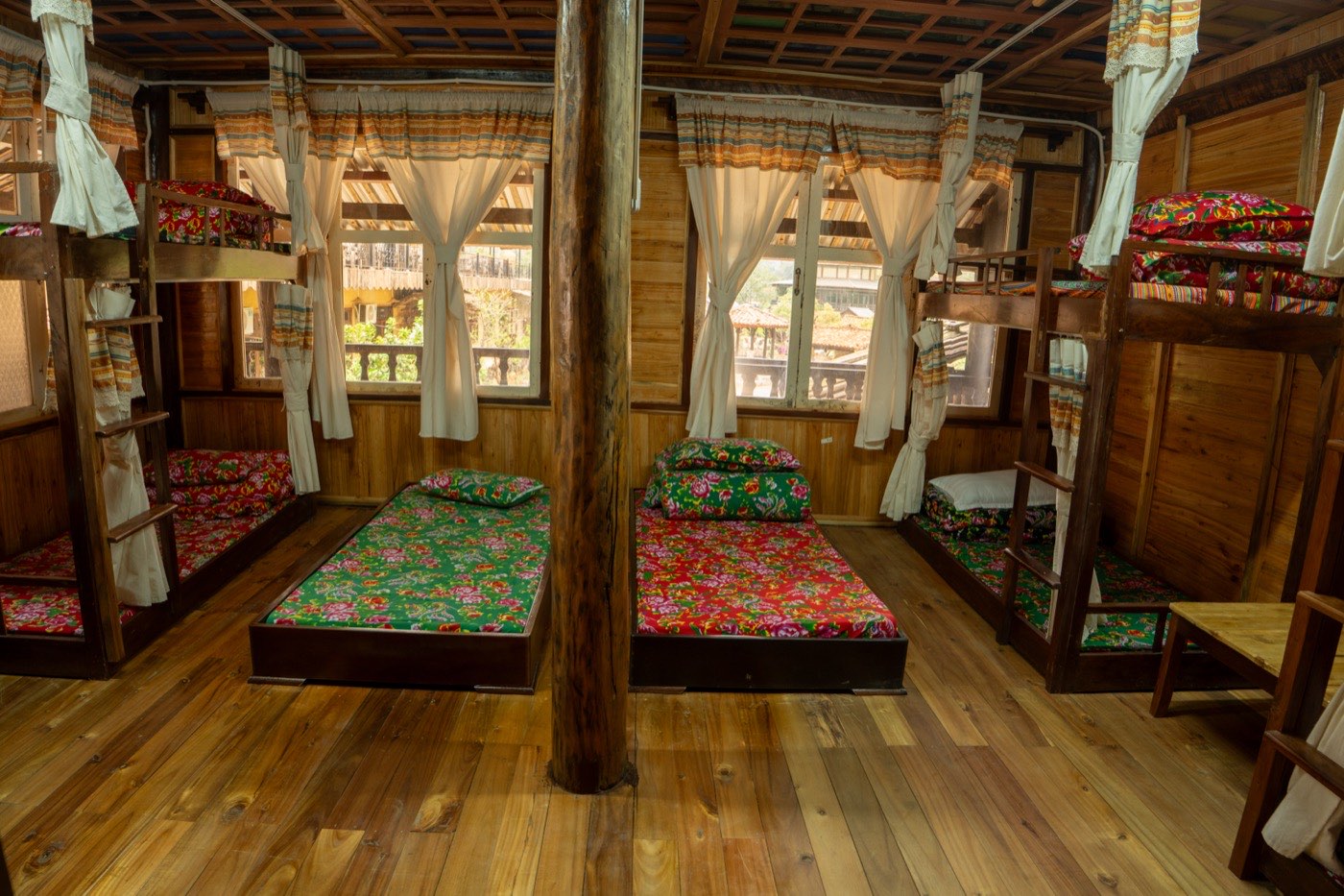 Phòng tập thể Dorm — nhà sàn gỗ với giường tầng và chăn đệm thổ cẩm